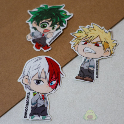 Handmade vinyl stickers of Bakugo, Midoriya, and Todoroki from My Hero Academia, illustrated by Avocado Artt in a cohesive trio design featuring each hero in their signature poses and outfits.